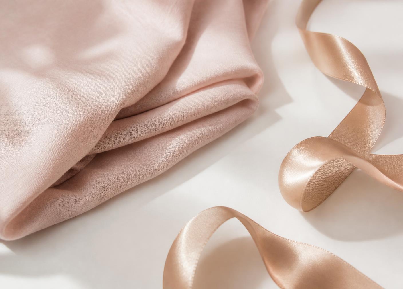 Soft blush fabric and champagne ribbon on a warm white surface
